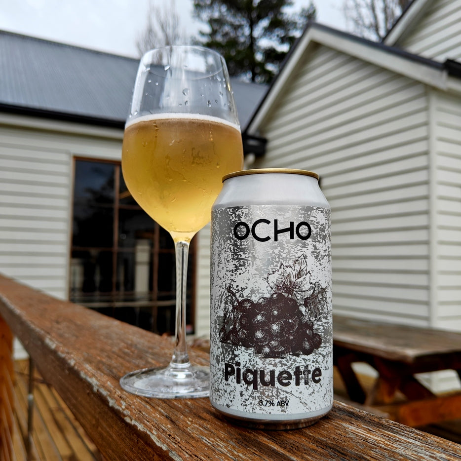 This is a photo of a can and a glass of a sour beer called Piquette. The beer in the glass is a light colour.